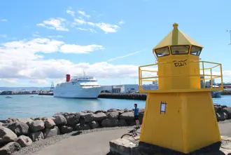 Reykjavík Harbor view of small yellow lighthouse and cruise ship in background.